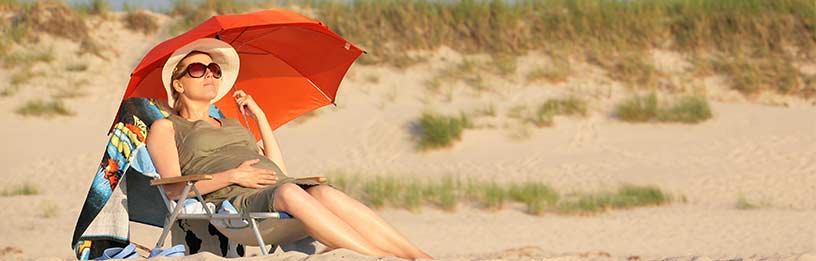 Pregnant woman on beach with umbrella