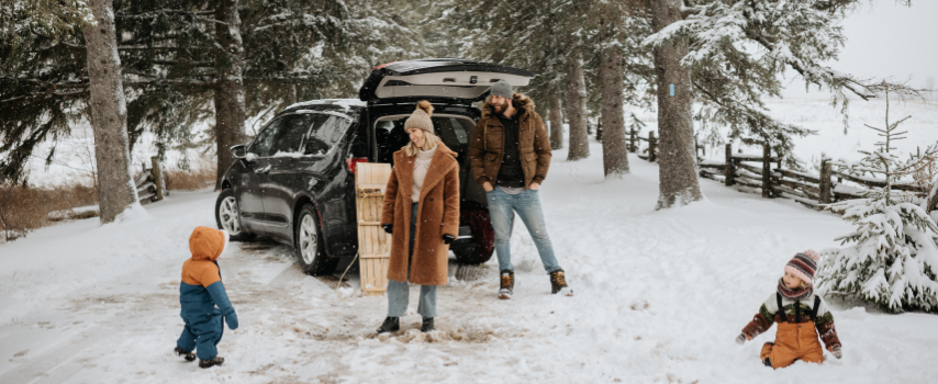 Young family playing in the snow during winter road trip
