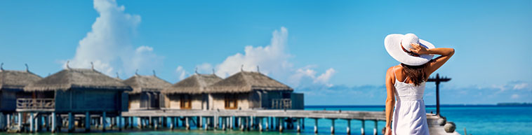 Woman walking on a walkway over blue ocean in the Madives