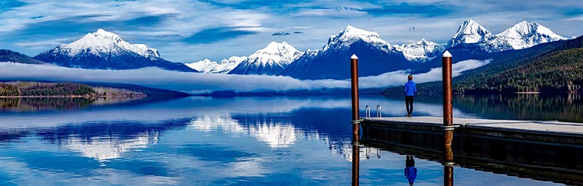Person standing on lake pontoon looking at mountain